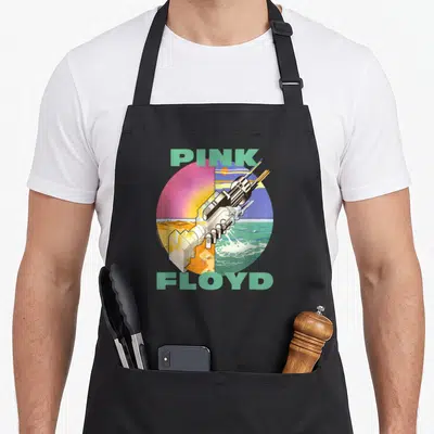 Tablier de cuisine noir avec illustration prise électrique et texte Pink Floyd sur fond circulaire coloré.