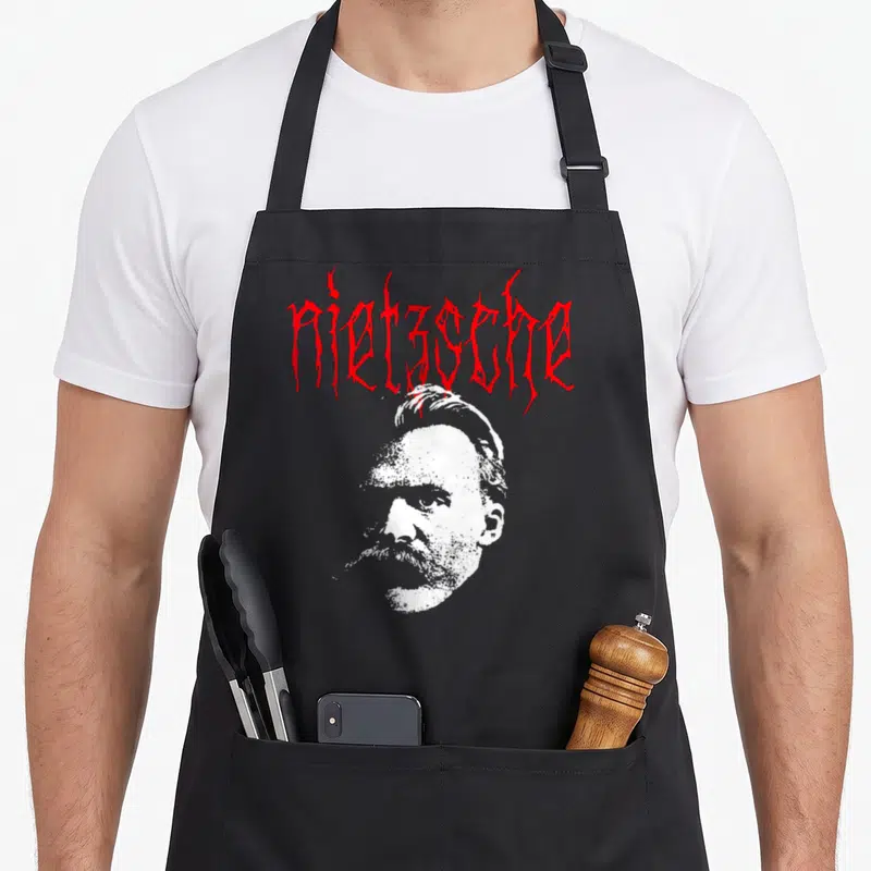 Tablier de cuisine noir avec portrait stylisé de Nietzsche et texte rouge en écriture gothique metal.