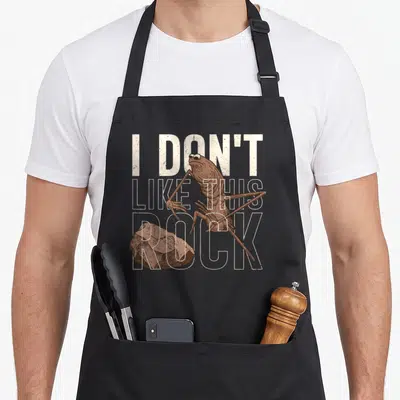 Tablier de cuisine noir avec illustration de ver Marc et texte I Don't Like This Rock en blanc.
