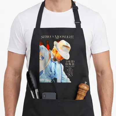 Tablier de cuisine noir avec une illustration de David Bowie portant un chapeau blanc et le texte Serious Moonlight.
