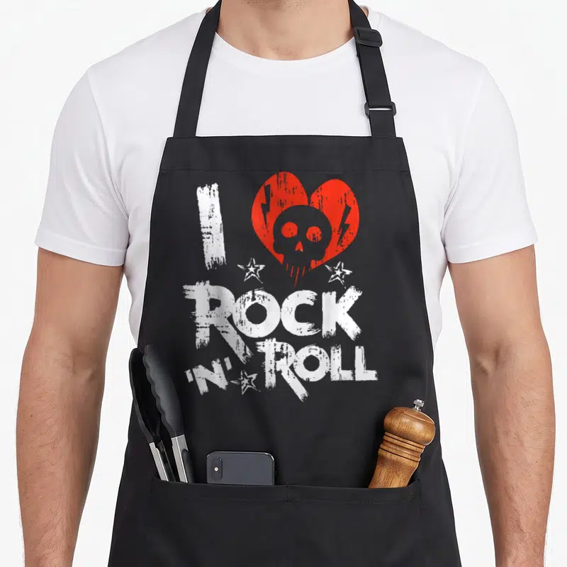 Tablier de cuisine noir avec inscription rock and roll, cœur rouge, crâne gris et étoiles blanches au style brushé.