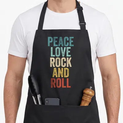 Tablier de cuisine noir avec Peace Love Rock And Roll en lettres colorées verticales style vintage.