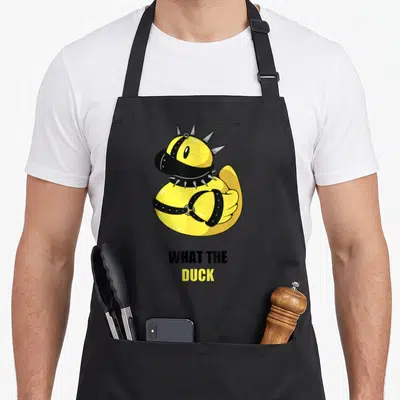 Tablier de cuisine noir avec un canard jaune portant un collier de spikes BDSM et le texte What the Duck imprimé en dessous.