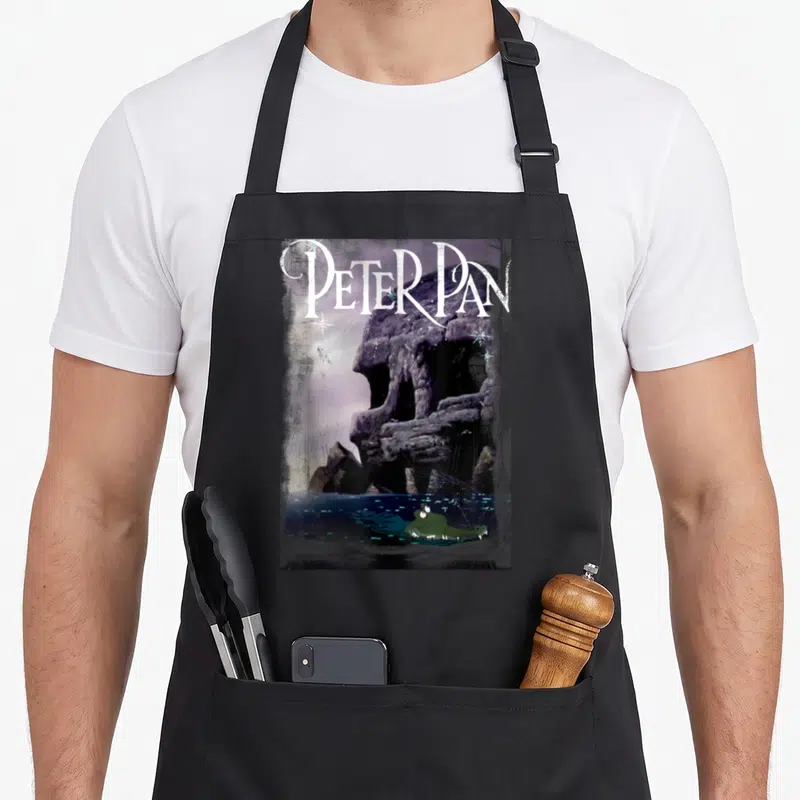 Tablier de cuisine noir avec illustration du croc de Peter Pan et du titre en blanc.