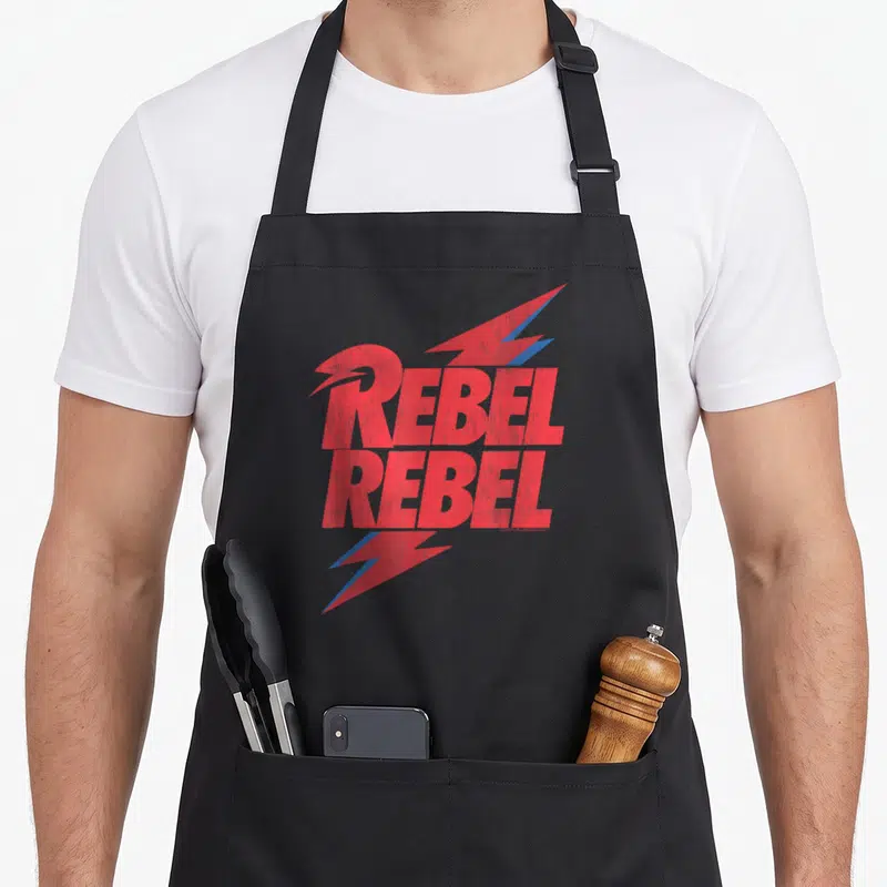 Tablier de cuisine noir avec l'inscription Rebel Rebel en rouge et des éclairs bleus stylisés.