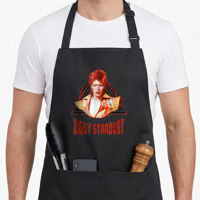Tablier de cuisine noir avec portrait de Ziggy Stardust et texte ZIGGY STARDUST en rouge.