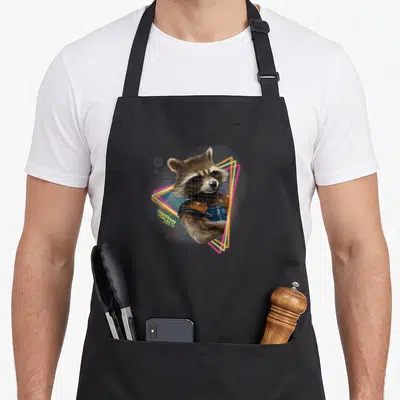 Tablier de cuisine noir avec illustration du renard Rocket Raccoon encadré par des triangles lumineux néon roses et jaunes sur fond gris.