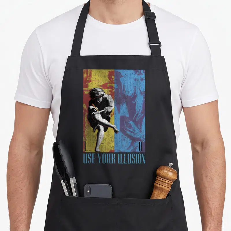 Tablier de cuisine noir avec une illustration graphique bicolore représentant un guitariste en pleine action et le texte Use Your Illusion.
