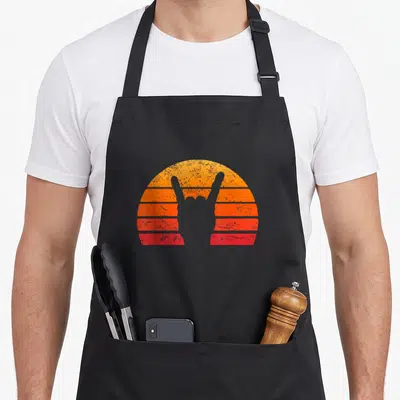 Tablier de cuisine noir avec une main de metal grise sur fond de soleil rayé orange et rouge au style rétro.