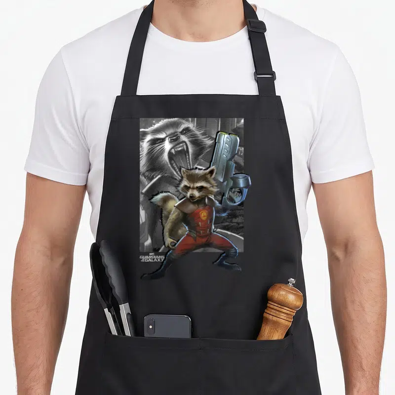 Tablier de cuisine noir avec illustration colorée de Rocket Raccoon tenant une arme futuriste devant un visage en grisaille.