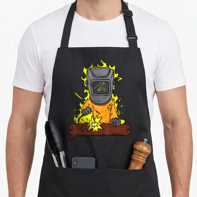 Tablier de cuisine noir avec illustration d'un soudeur enveloppé de flammes jaunes et orange.