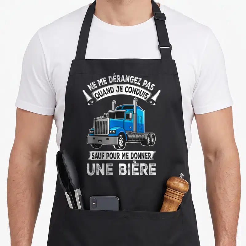 Tablier de cuisine noir avec illustration de camionneur bleu et texte humoristique sur fond uni.