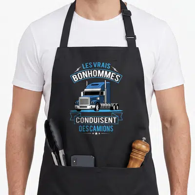 Tablier de cuisine noir avec illustration de camion bleu et texte Les vrais bonhommes conduisent des camions en blanc et bleu.