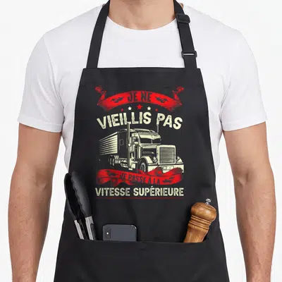 Tablier de cuisine noir avec illustration de camion américain et texte Je ne vieillis pas je passe à la vitesse supérieure en rouge et blanc.
