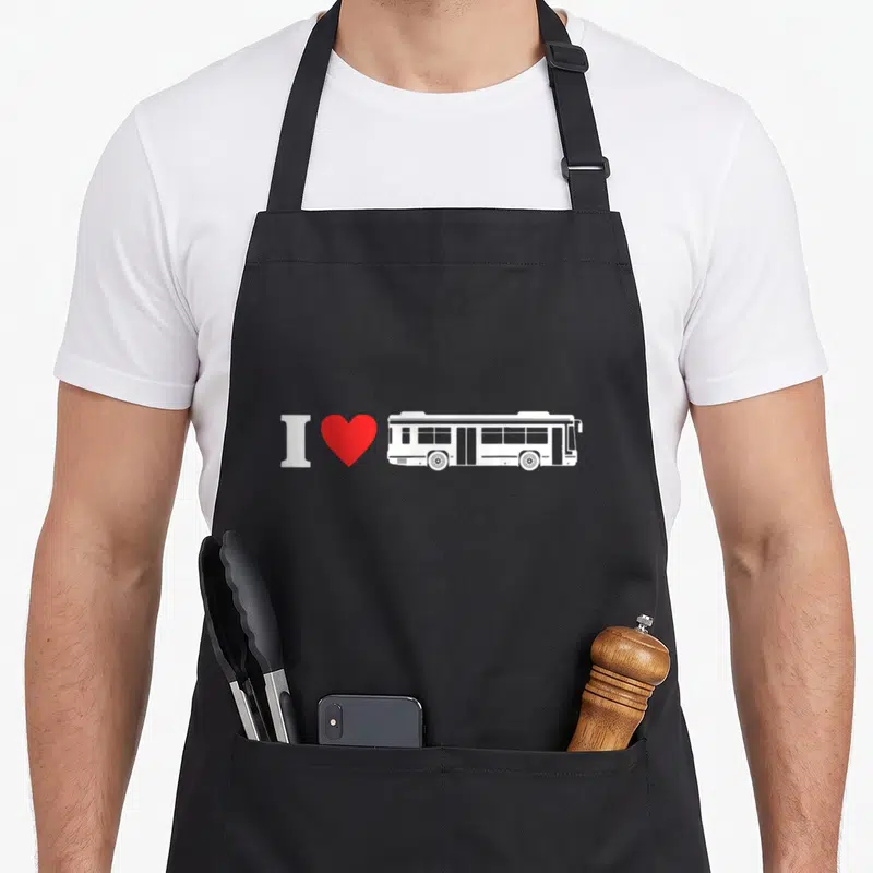 Tablier de cuisine noir avec un autobus blanc, un cœur rouge et le texte I Love Bus Driving imprimé au centre.
