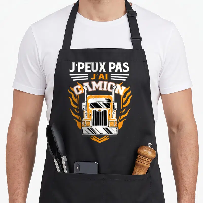 Tablier de cuisine noir avec illustration d'un camion orange et texte J'peux pas j'ai camion entouré de flammes oranges.