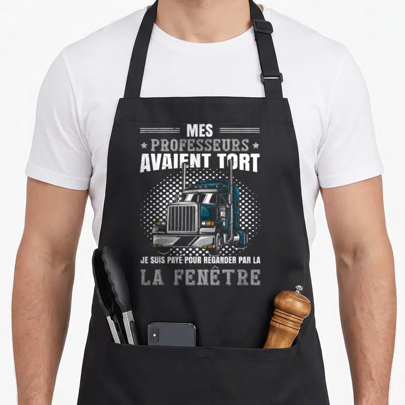 Tablier de cuisine noir avec illustration de camion bleu et texte humoristique sur la route.