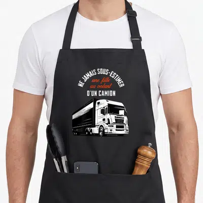 Tablier de cuisine noir avec illustration de camion routier et texte blanc et orange sur fond uni.