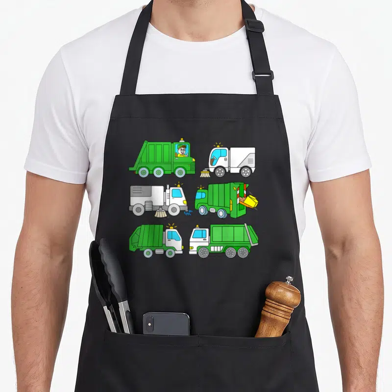 Tablier de cuisine noir avec six illustrations de camions poubelles et balayeuses vertes et blanches en style cartoon enfant.