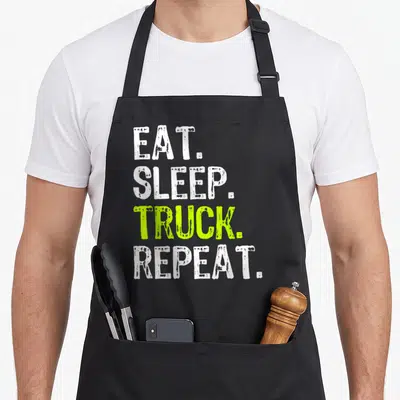 Tablier de cuisine noir avec inscription Eat Sleep Truck Repeat en blanc et vert vif sur fond uni.
