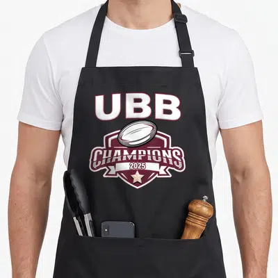 Tablier de cuisine noir avec un logo UBB Champions 2025 en bordeaux et blanc.
