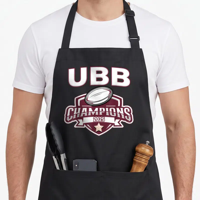 Tablier de cuisine noir avec un logo UBB Champions 2025 en bordeaux et blanc.