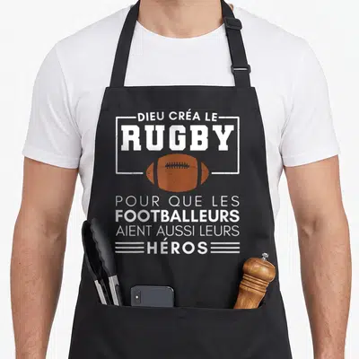 Tablier de cuisine noir avec inscription blanche et ballon de rugby orange au centre du motif imprimé.