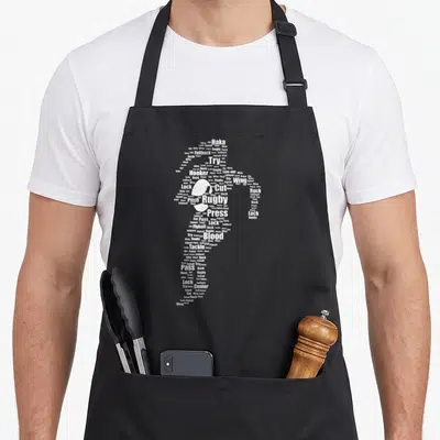 Tablier de cuisine noir avec une silhouette féminine constituée de mots blancs liés au rugby tels que Try, Pass, Tackle et Blood.