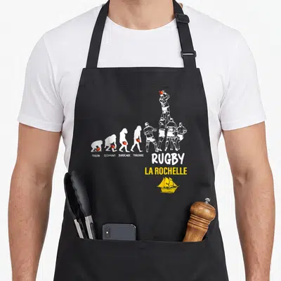 Tablier de cuisine noir avec illustration évolution rugby citant Toulon Clermont Bordeaux Toulouse et La Rochelle en bas.