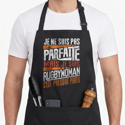 Tablier de cuisine noir avec inscription Je ne suis pas parfaite mais je suis rugbywoman en blanc et orange.