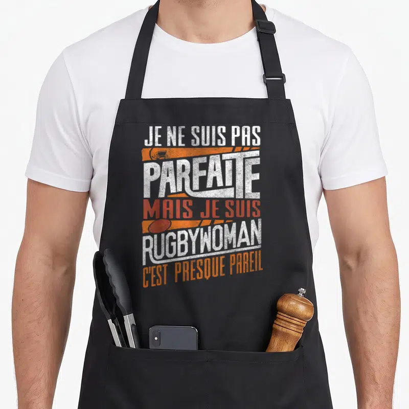 Tablier de cuisine noir avec inscription Je ne suis pas parfaite mais je suis rugbywoman en blanc et orange.