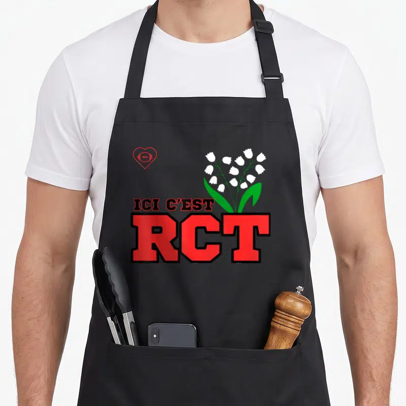 Tablier de cuisine noir avec le logo Ici c'est RCT et des lys blancs sur fond gris uni