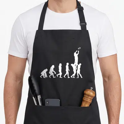 Tablier de cuisine noir avec silhouette blanche représentant l'évolution humaine vers le rugby et un ballon ovale.