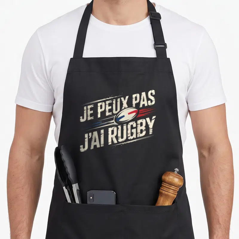 Tablier de cuisine noir avec l'inscription Je peux pas j'ai rugby et un ballon stylisé aux couleurs du drapeau français.