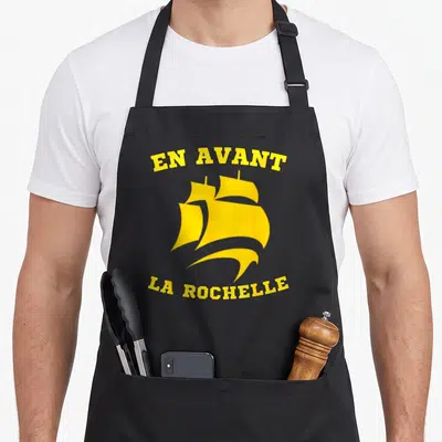 Tablier de cuisine noir avec un navire jaune et le texte En Avant La Rochelle imprimé en arc de cercle.