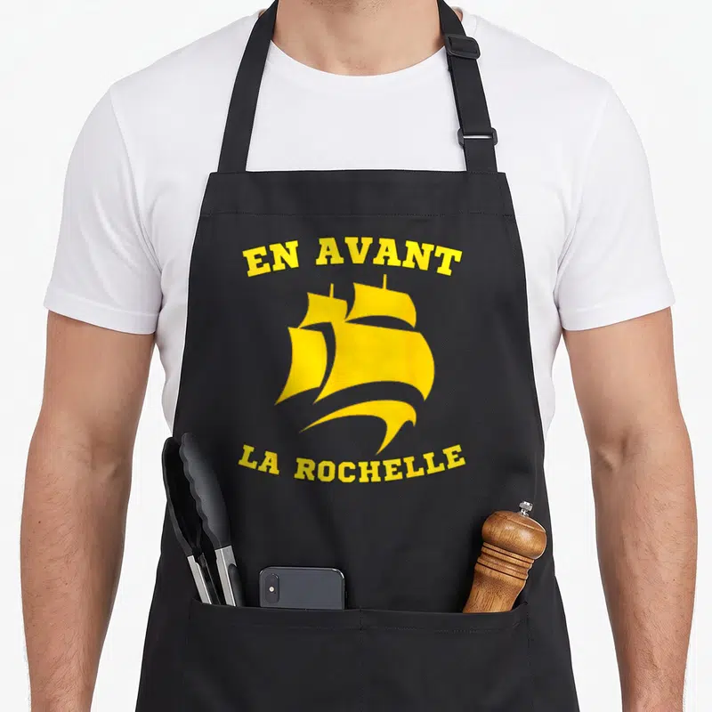 Tablier de cuisine noir avec un navire jaune et le texte En Avant La Rochelle imprimé en arc de cercle.
