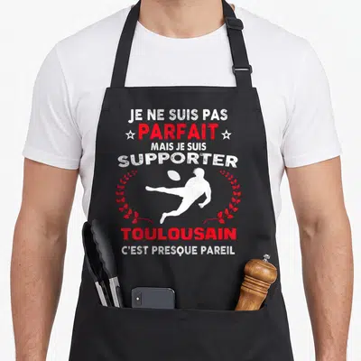 Tablier de cuisine noir avec silhouette blanche de joueur de rugby et texte humoristique en blanc et rouge.