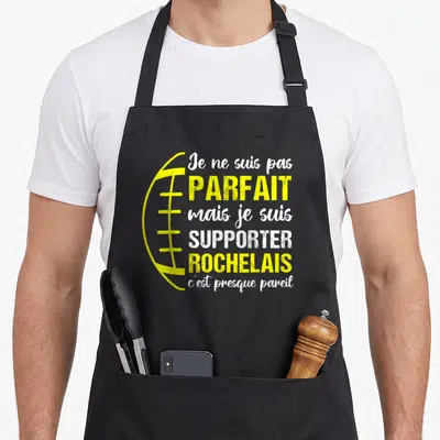 Tablier de cuisine noir avec illustration de ballon de rugby jaune et texte blanc et jaune sur fond uni.