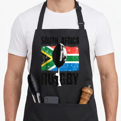 Tablier de cuisine noir avec drapeau sud-africain, ballon de rugby et texte South Africa Rugby en style vintage.