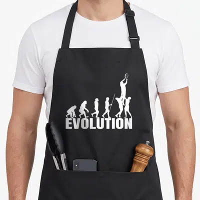 Tablier de cuisine noir avec une illustration blanche représentant l'évolution humaine se terminant par un joueur de rugby sautant pour attraper le ballon.