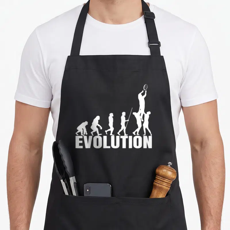 Tablier de cuisine noir avec une illustration blanche représentant l'évolution humaine se terminant par un joueur de rugby sautant pour attraper le ballon.