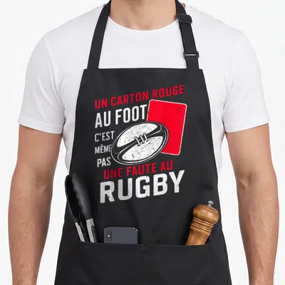 Tablier de cuisine noir avec un ballon de rugby, un carton rouge et le texte humoristique sur le sport.