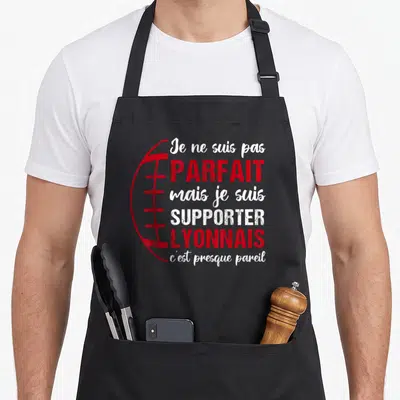 Tablier de cuisine noir avec texte blanc et rouge et dessin de ballon de rugby sur le devant.