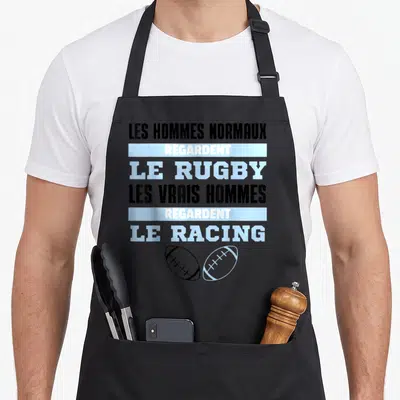 Tablier de cuisine noir avec le texte Les hommes normaux regardent le Rugby et deux ballons de rugby stylisés en bas.