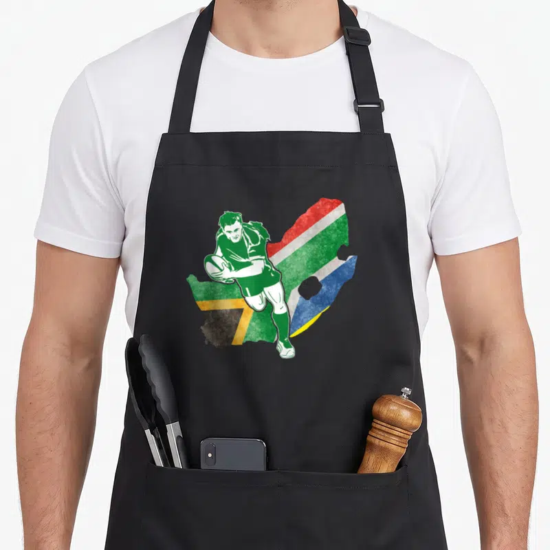 Tablier de cuisine noir avec un joueur de rugby en vert devant une carte d'Afrique du Sud aux couleurs du drapeau.