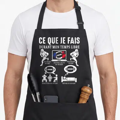 Tablier de cuisine noir avec illustration blanche montrant des joueurs et un écran d'ordinateur sur fond gris uni.