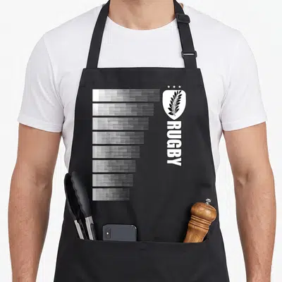 Tablier de cuisine noir avec motif blanc vertical imitant des rayures de maillot et un insigne à la feuille d'argent surmonté de trois étoiles.