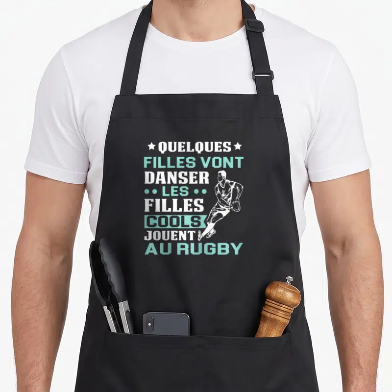 Tablier de cuisine noir avec inscription blanche et turquoise sur le rugby et silhouette d'une joueuse en mouvement.