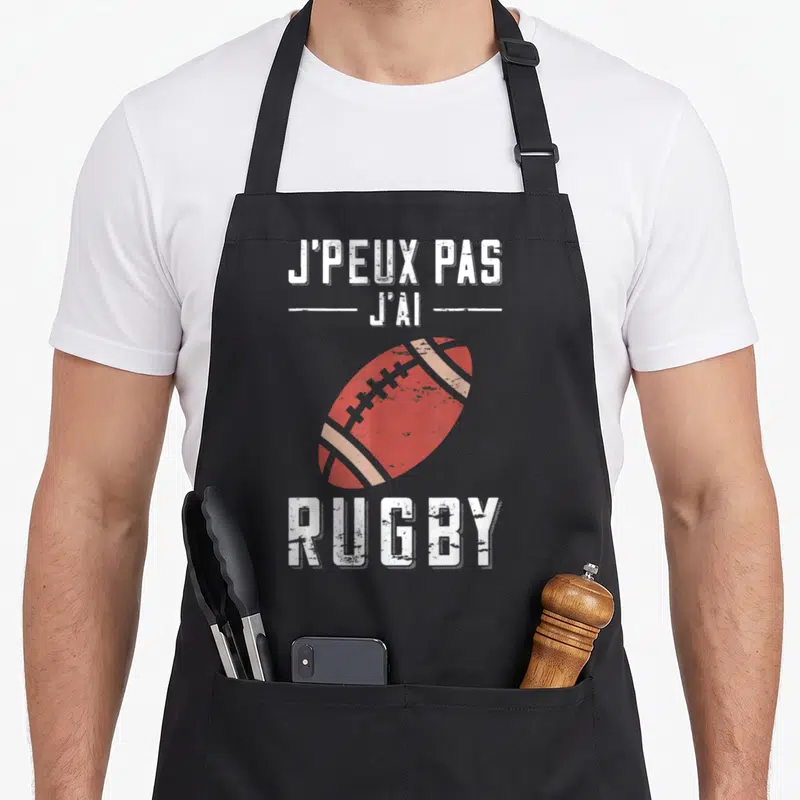 Tablier de cuisine noir avec inscription J'peux pas j'ai rugby et illustration ballon de rugby rouge délavé