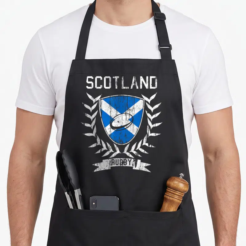 Tablier de cuisine noir avec un blason écossais bleu et blanc encadré de lauriers blancs et le texte SCOTLAND RUGBY en haut et en bas.
